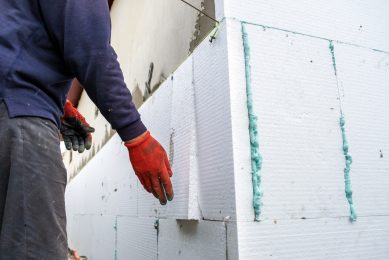 construction worker insulating a building with polystyrene foam